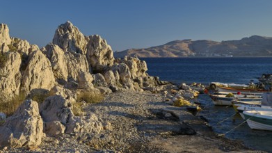 Rocky landscape by the sea with boats and view of distant mountain ranges, bay, Charaki, Haraki,