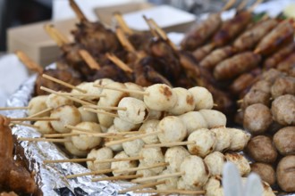 Close up of white Thai fish or chicken meat balls grilled skewers at street food market