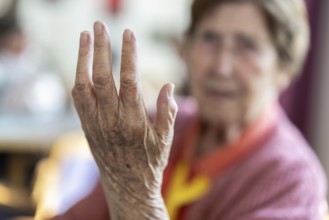 Over 90-year-old senior citizen with dementia talks and gesticulates with her wrinkled hands in a