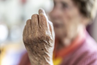 Over 90-year-old senior citizen with dementia talks and gesticulates with her wrinkled hands in a
