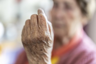 Over 90-year-old senior citizen with dementia talks and gesticulates with her wrinkled hands in a