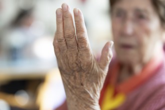 Over 90-year-old senior citizen with dementia talks and gesticulates with her wrinkled hands in a