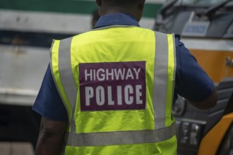 Back view of a highway police officer wearing a neon reflective vest, Dhaka, Bangladesh