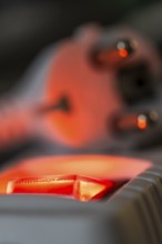 Close-up of a white power plug, Schuko plug, on a multiple socket with red indicator light,