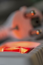 Close-up of a white power plug, Schuko plug, on a multiple socket with red indicator light,
