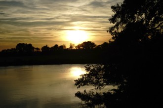 A peaceful sunset over a lake, trees against the evening sky, natural landscape in Wüsting, 27798