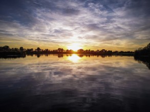 A colourful sunset is reflected in the calm waters of a lake, natural landscape in Wüsting, 27798