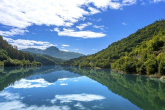 The tranquil waters of ibiur reservoir mirror the vibrant blue sky and fluffy white clouds,