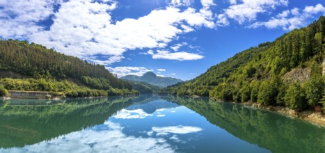 The serene ibiur reservoir mirrors the sky and surrounding hills, creating a tranquil panorama of