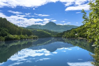The calm waters of ibiur reservoir perfectly mirror the vibrant blue sky and lush green mountains