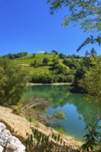 The tranquil waters of ibiur reservoir mirror the vibrant green hills and clear blue sky of the