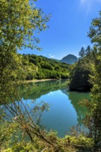 The calm waters of ibiur reservoir reflect the surrounding green hills and vibrant blue sky,