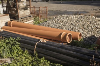 Borken, NRW, Germany, Orange and black plastic pipes are lying on a construction site, waiting to