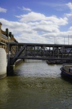 Steel bridge with boats, in sunny weather and clouds in the sky. View from the Landungsbrücken in