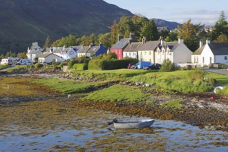 A quiet seaside village with colourful houses, a boat in the water and a green landscape against a