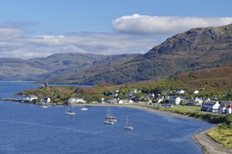Coastal town with sailing boats at the harbour, mountains in the background, under blue sky, Kyle