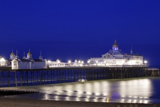 Illuminated pier at night with reflecting lights in the water, Victorian, Bournemouth, England,