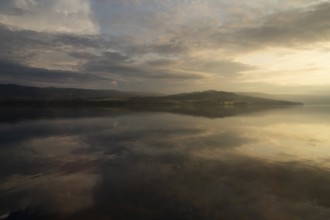 The sky and clouds are reflected on the surface of Lake Mjøsa or Mjosa just in front of sunset,