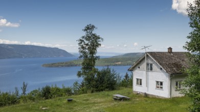 White house in a meadow, view opens onto Lake Mjøsa or Mjosa and forested mountain ridges, Olavsweg