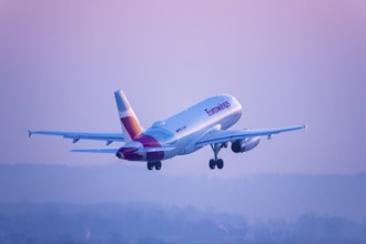 A Eurowings aircraft soars in a pink-coloured sky, Stuttgart, Baden-Württembwerg, Germany