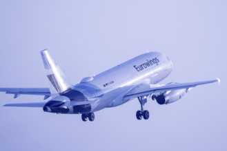 A Eurowings aeroplane takes off into the sky in blue light, Stuttgart, Baden-Württembwerg, Germany