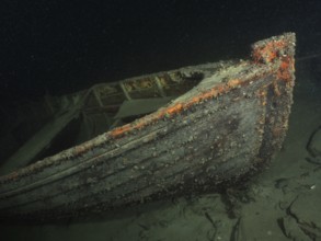 Wreck of a rowing boat lies on the sandy lake bottom in the dark water, dive site Schoggiwand, Lake