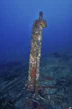 Old rusty part of a shipwreck standing on the seabed, surrounded by blue waters. Dive site wreck Le