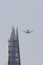 Jet passenger aircraft in flight over The Shard skyscraper building, London, England, United