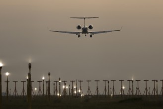 Bombardier Global business jet passenger aircraft in flight landing at sunset at London Stansted