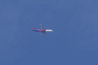 Airbus A321 jet aircraft of Wizz Air airlines in flight in a blue sky, England, United Kingdom