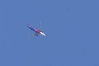 Airbus A321 jet aircraft of Wizz Air airlines in flight in a blue sky, England, United Kingdom