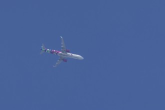Airbus A321 jet aircraft of Wizz Air airlines in flight in a blue sky, England, United Kingdom