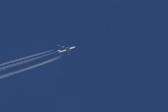 Boeing 747 Jumbo jet cargo aircraft in flight in a blue sky with vapour trails or contrails behind,