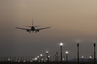 Boeing 737 jet passenger aircraft of Ryanair airlines landing over runway lights at sunset, London