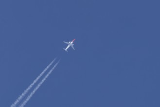 Boeing 737 jet passenger aircraft of Norweign Air with a vapour trial or contrail behind flying in