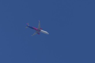 Airbus A321 jet aircraft of Wizz Air airlines in flight in a blue sky, England, United Kingdom