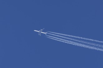 Airbus A340-300 jet aircraft of Lufthansa airlines in flight in a blue sky with vapour trails or