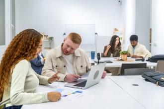 Young diverse professionals collaborating at a meeting table, discussing business strategies,