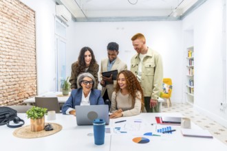 Diverse business team is collaborating and actively discussing financial data shown on a laptop