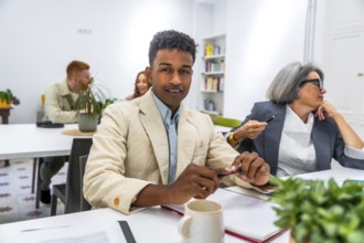 Young african american man smiling at the camera during a business meeting, with other diverse