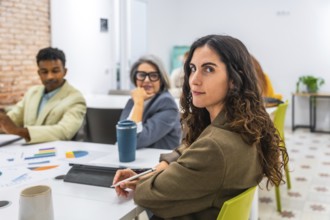 Young businesswoman with curly hair is looking back at the camera while attending a business