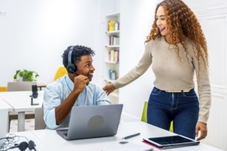 Multiracial coworkers smiling and interacting in a modern office, with a man wearing a headset
