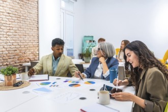 Multiracial business professionals discussing colorful charts and data analytics during a