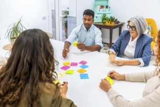 Diverse business team collaborating and exchanging ideas in a creative meeting, using colorful