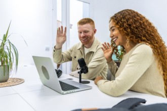 Diverse young adult man and woman smiling and waving while actively recording a podcast or