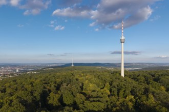Modern television tower above a green forest and soft clouds in the blue sky, Stuttgart-Degerloch,