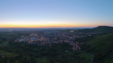 Panoramic view of a town at sunset, with illuminated streets and surrounding hills, Korb im