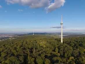 The television tower above a wooded area shows a clear sky and scattered clouds,