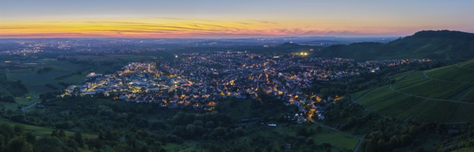 Panoramic view of a town at dusk, illuminated streets and surrounding hills, Korb im Remstal,