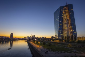 The lights of the European Central Bank (ECB) and the Frankfurt banking skyline glow in the